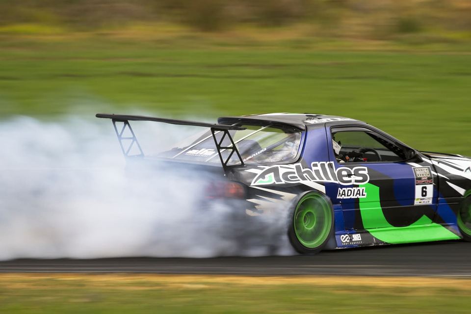 Liveried drift car at full opposite lock, half hidden in smoke
