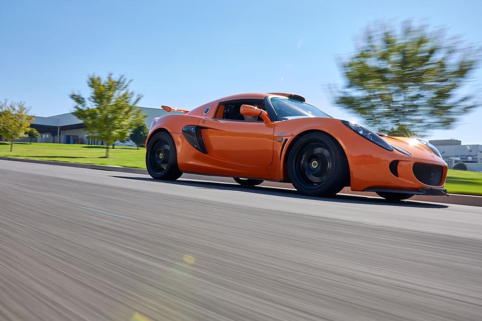 Orange sports car cornering under a bright blue sky