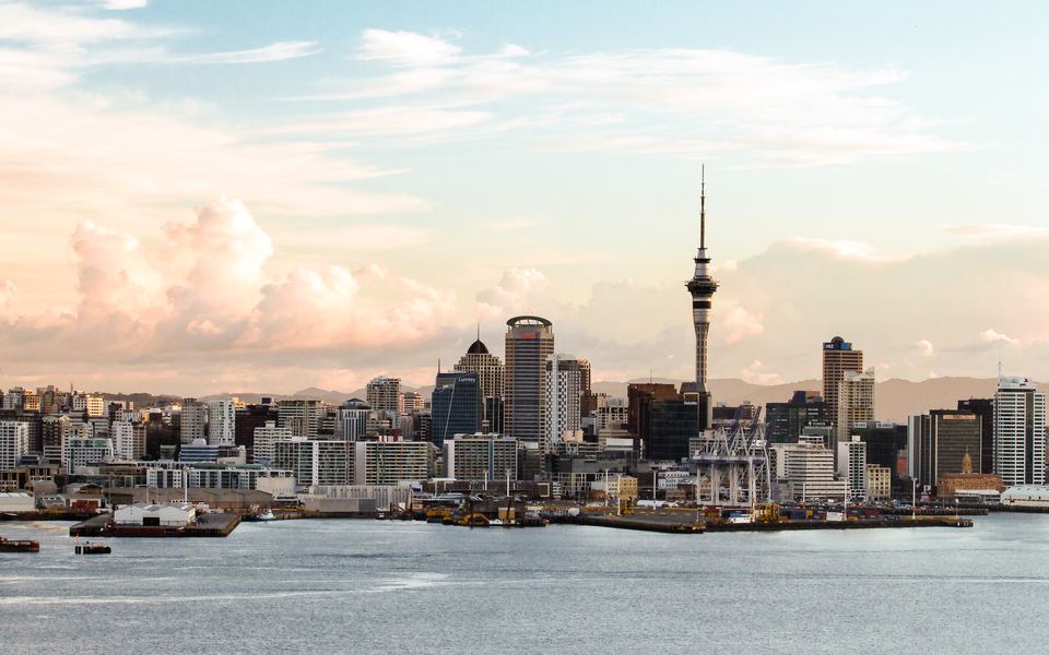 City skyline with a tall tower at dusk across the harbour
