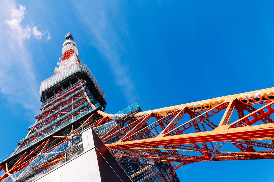 Red and white lattice tower and steel framework against a deep blue sky