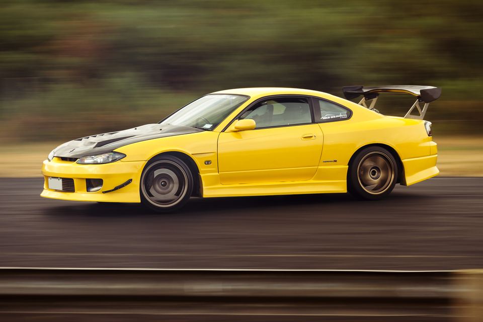 Yellow coupe with a rear wing panned at a slow shutter speed