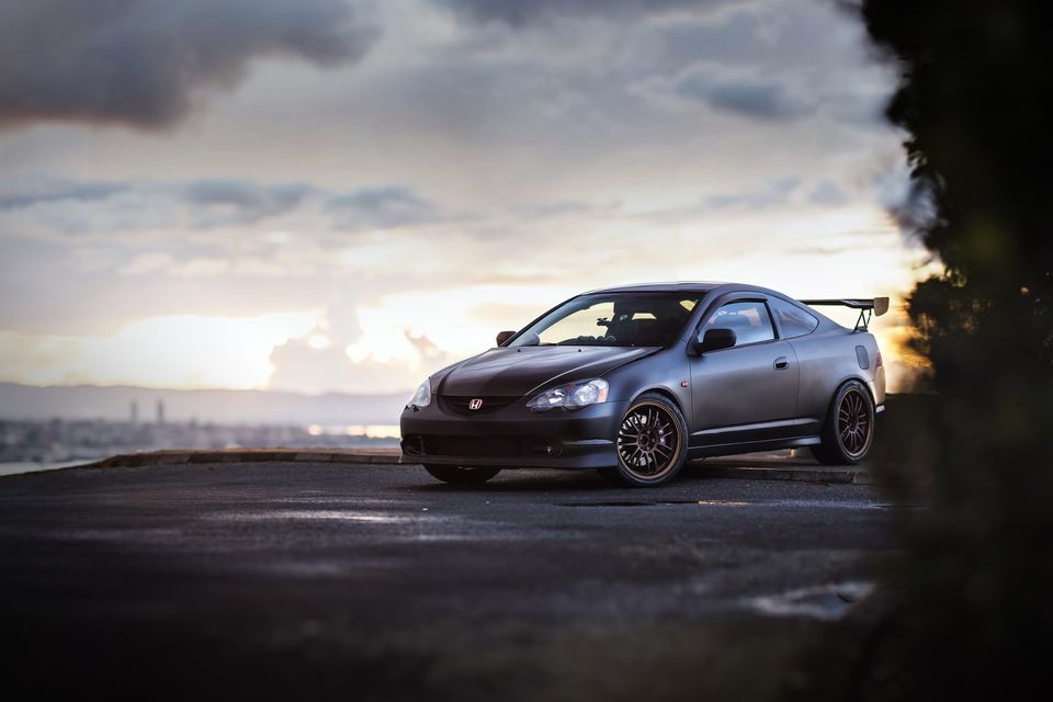 Dark grey hatchback parked under a dramatic sunset sky