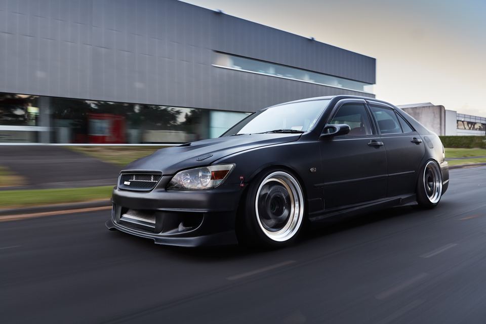 Black sedan parked on dark tarmac under an overcast sky