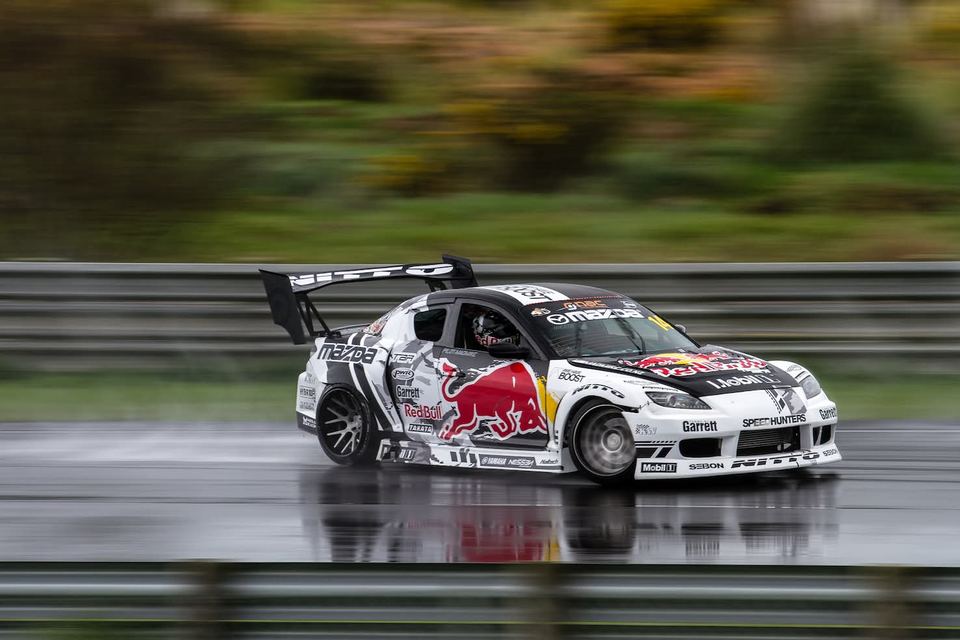 Blue, red and silver liveried drift car sliding close to the wall